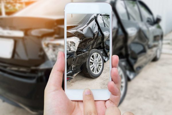 Insurance policyholder submitting auto claim with smartphone to be processed with AI.